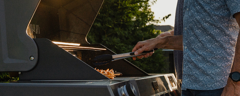 Person grilling outdoors with a focus on the grill and food