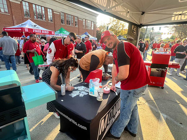 People at an outdoor event with a table and branding visible