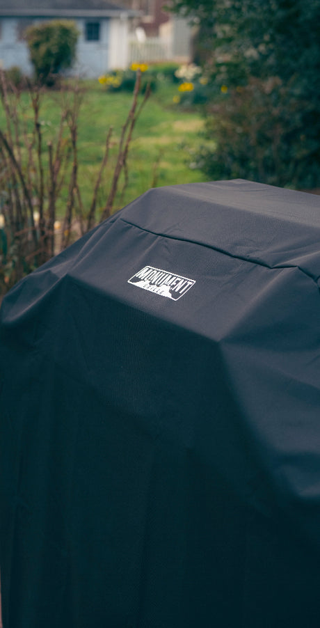 Black grill cover with a brand logo on a blurred garden background
