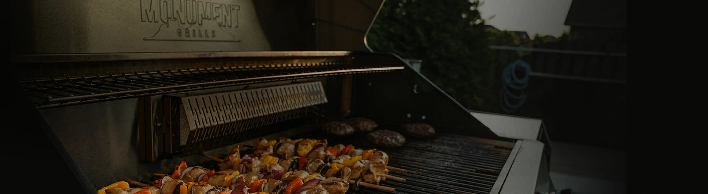 Grill with skewers and burgers on a dark background