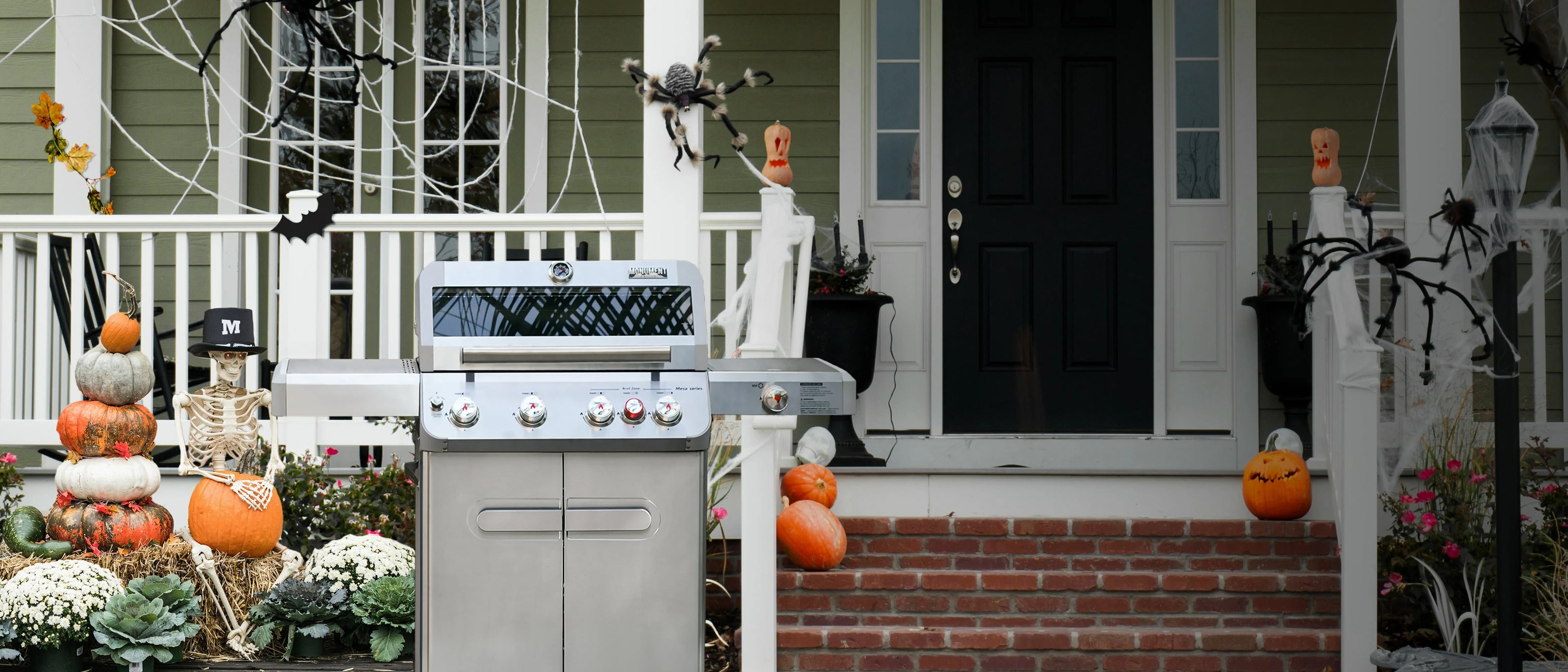 Outdoor grill on a porch decorated for Halloween with pumpkins and spider webs.