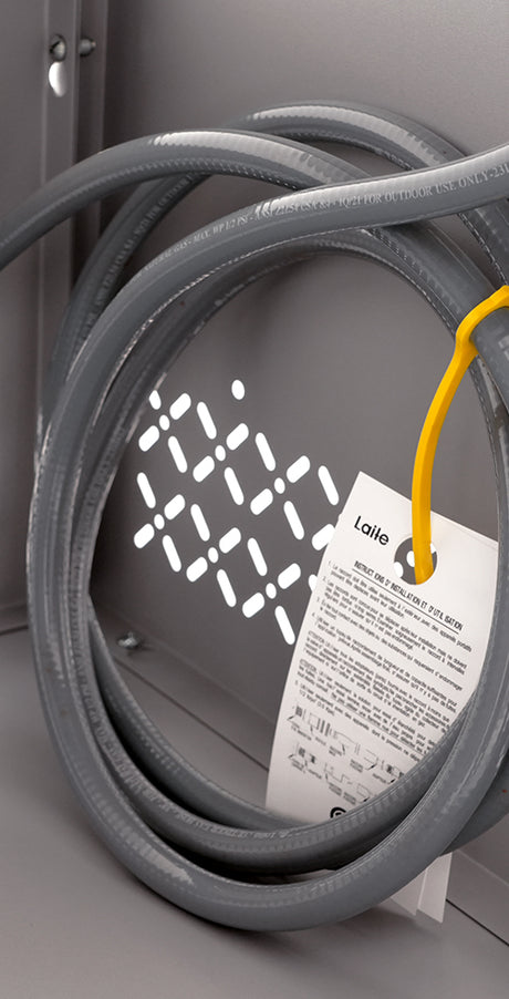 Gray coiled cable with a yellow tag on a metallic surface