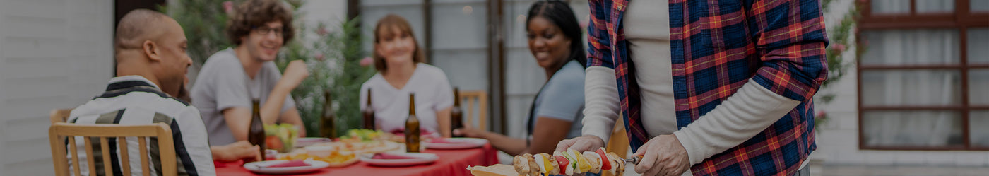 People sitting around a table with food, possibly at an outdoor event.