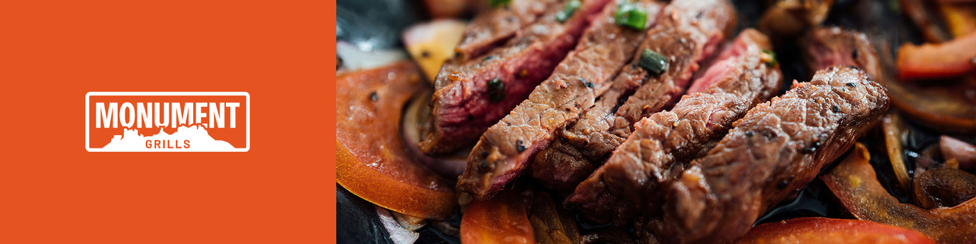 Steak dish with vegetables on a plate against an orange background with 'Monument Grills' logo.