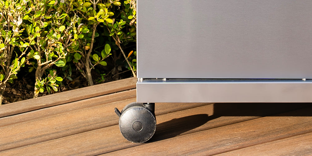 Metallic appliance on a wooden surface with greenery in the background