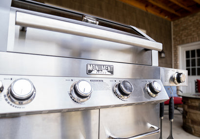 Stainless steel grill with 'Monument Grills' branding on an outdoor patio.
