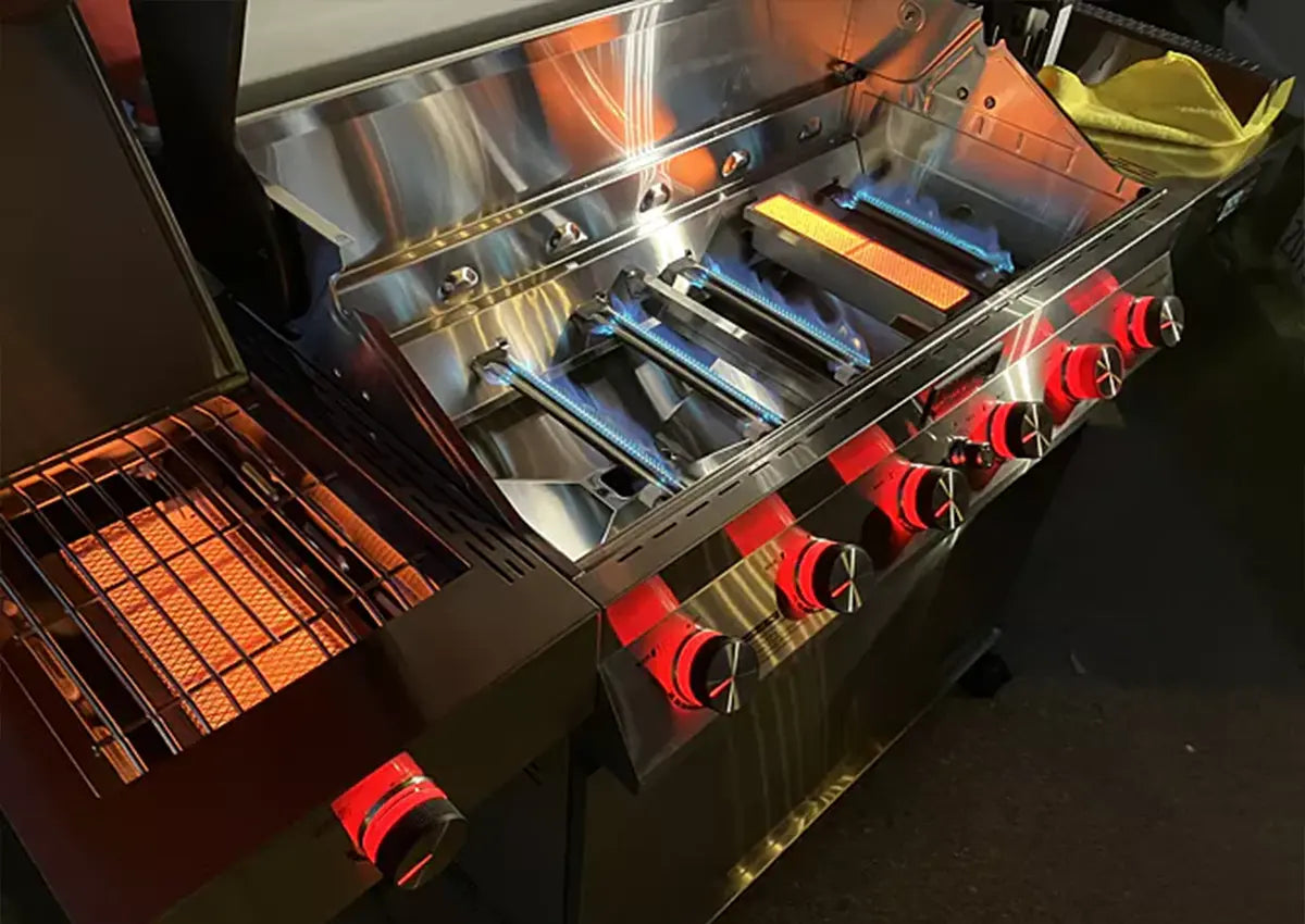 Close-up of a grill with glowing hot plates and various tools on a dark background