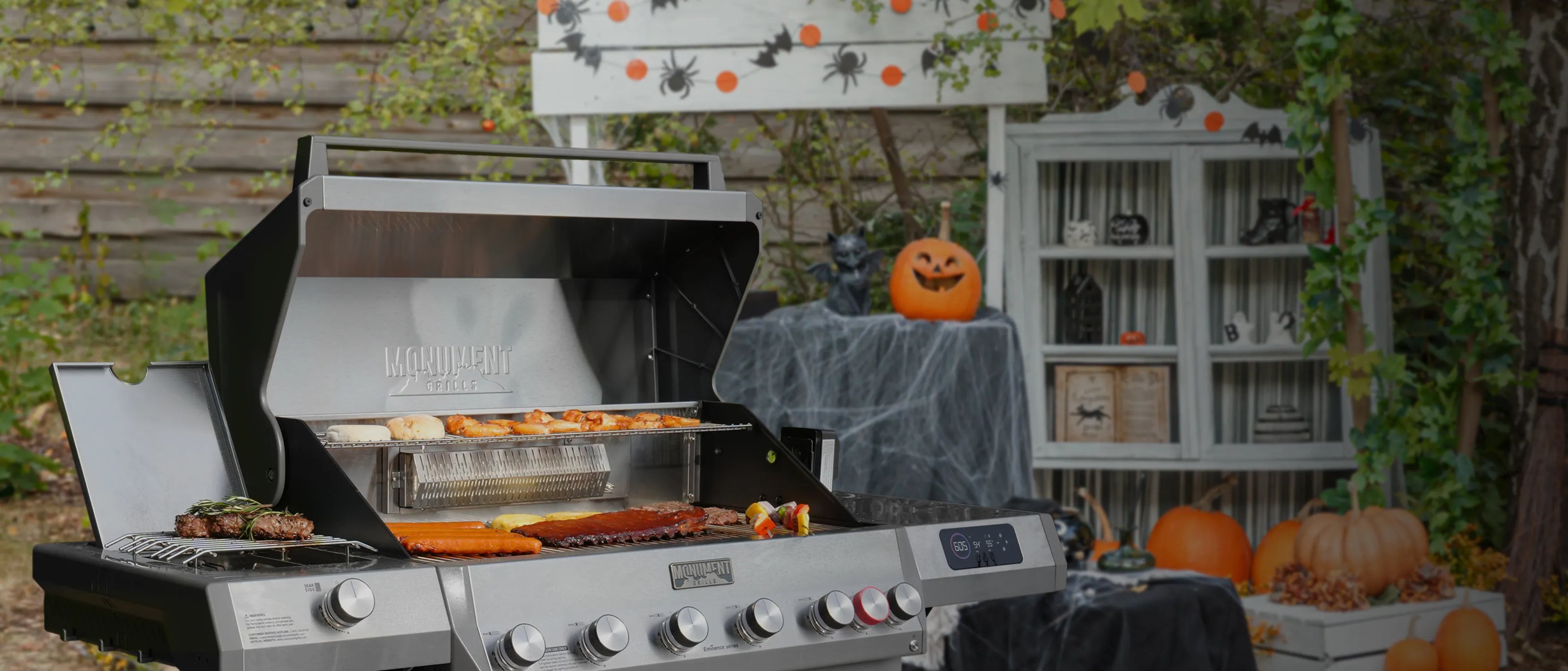 Outdoor grill setup with Halloween decorations including pumpkins and a ghost.