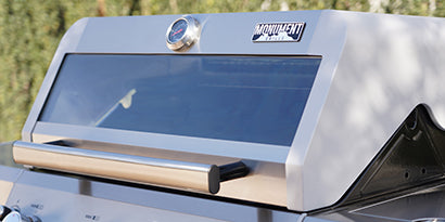 Grill with 'Monument' branding on a blurred outdoor background