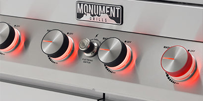 Control panel with knobs and 'Monument Grills' logo on a white background