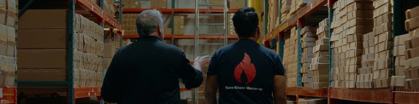 Two people walking through a warehouse with shelves and boxes.