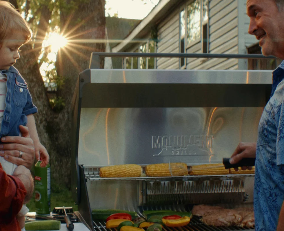 Man and child grilling vegetables on a  grill outdoors