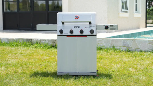 Outdoor grill on grass with pool and house in the background