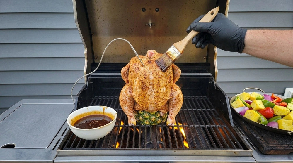 Person grilling a chicken on a barbecue with a brush and bowl nearby.