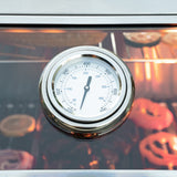 a grill thermometer showing the internal cooking temperature with food grilling in the background.