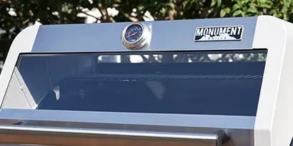 Close-up of a grill with a brand logo on a blurred natural background