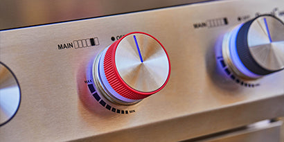 Close-up of a stove control panel with red and blue knobs.