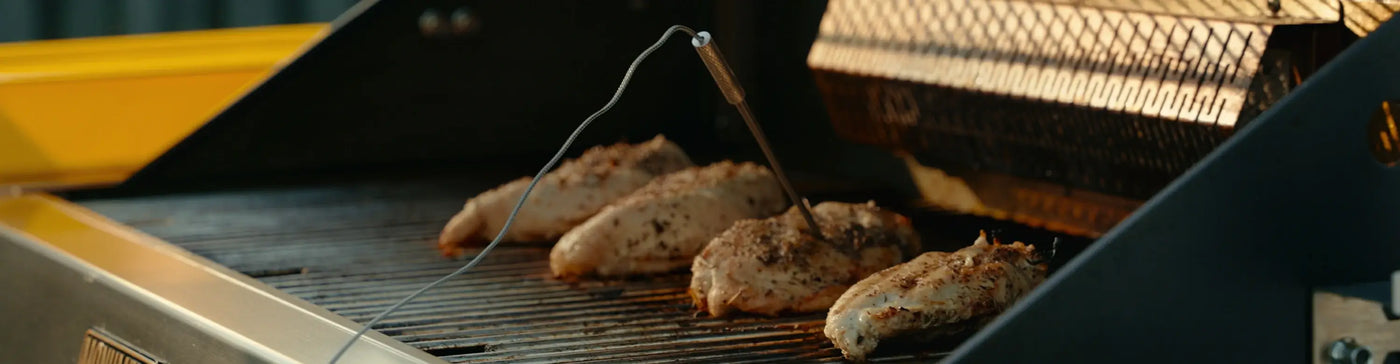 Chicken being grilled on a barbecue with a close-up view of the grill.