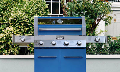 Blue outdoor grill with silver accents in a garden setting