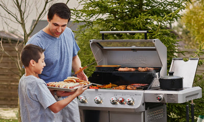 Man and boy grilling outdoors with a barbecue in the background