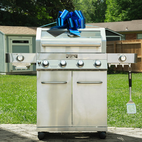 A stainless steel outdoor grill tied with a blue bow, presented as a Father’s Day gift in a backyard setting.